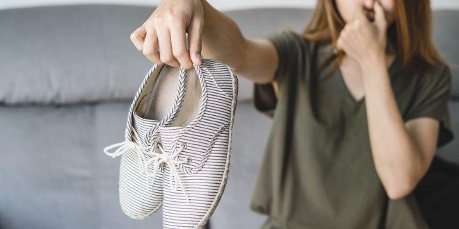 Junge Frau hält stinkende Schuhe von sich weg