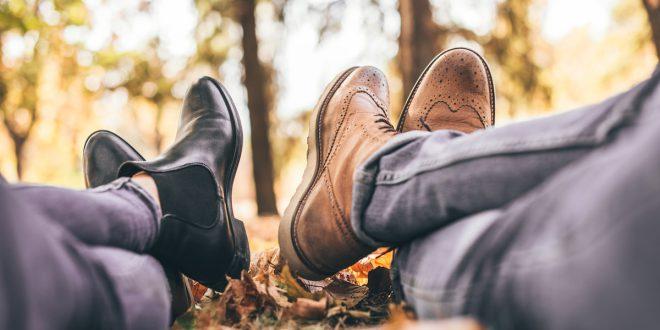 Zwie Personen liegen in herbstlichem Park auf dem Boden. Man sieht die Beine und Schuhe.