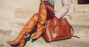 Closeup von Frau mit braunen Stiefeln und Lederrock. Die Frau sitzt auf einer Steintreppe