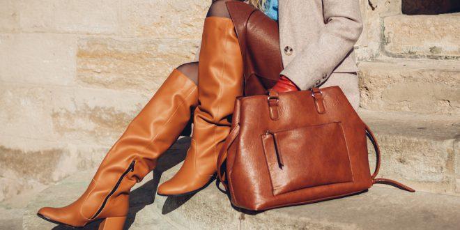 Closeup von Frau mit braunen Stiefeln und Lederrock. Die Frau sitzt auf einer Steintreppe